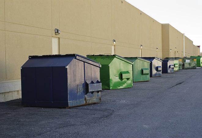 a forklift lifts a full dumpster from a work area in Albertville